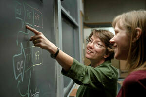 Professor Holly Goodson working with a student at a blackboard